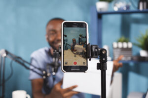 blogger making giveaway while live streaming smartphone screen closeup web content creator announcing contest showing prize gift using mobile phone tripod video recording